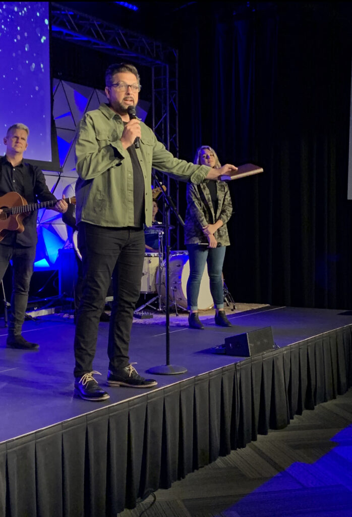 A man standing on stage with other people.